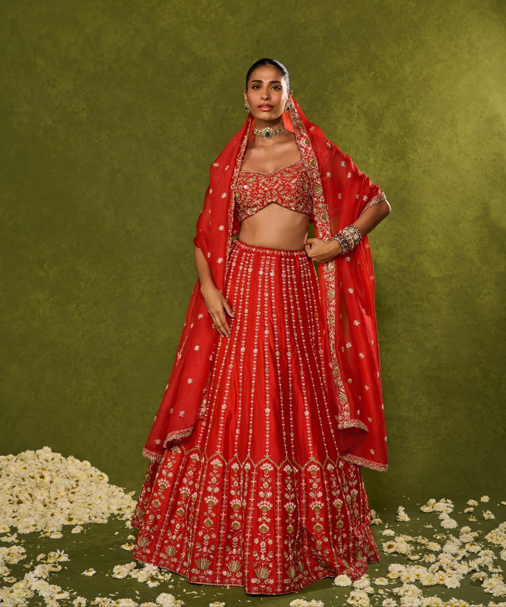 ANANDI LEHENGA - Red raw silk lehenga meticulously crafted with intricate resham, zardozi, pearl and glass beadwork paired with a zardozi-embellished floral work cap sleeve blouse -  Leher by Chamee and Palak