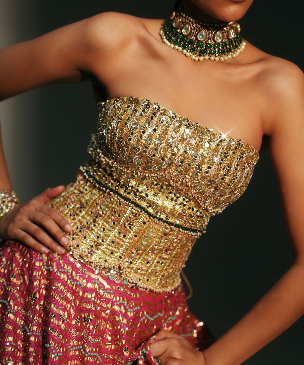 GARIMA - HAND EMBROIDERED RANI PINK LEHENGA WITH GOLDEN CORSET -  Mehfil by Mahima Mahajan