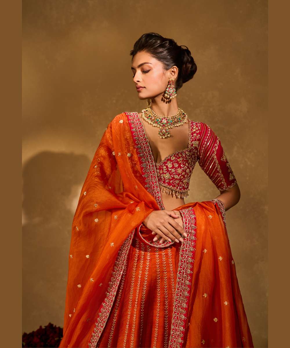 AARIANA LEHENGA - Orange to red ombré raw silk lehenga intricately embellished with zardozi, sequence ,glass beads and pearls paired with a delicately encrusted elbow-sleeve blouse - Leher by Chamee and Palak