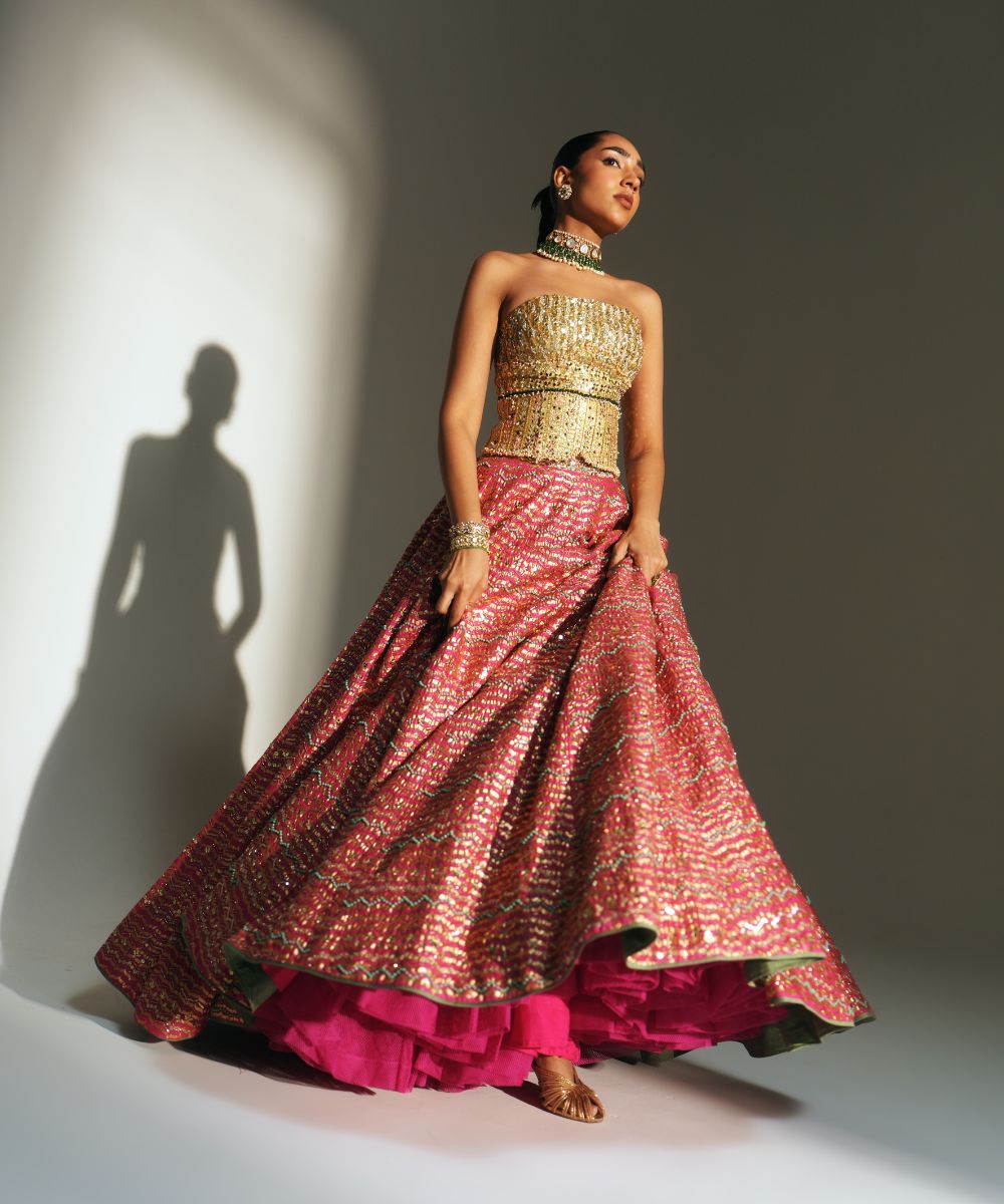 GARIMA - HAND EMBROIDERED RANI PINK LEHENGA WITH GOLDEN CORSET -  Mehfil by Mahima Mahajan