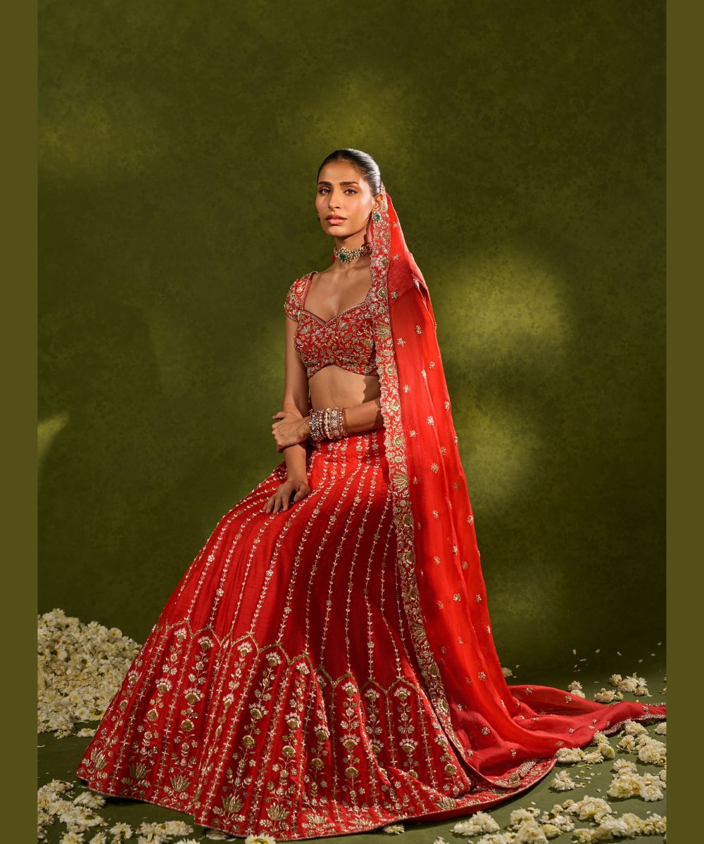 ANANDI LEHENGA - Red raw silk lehenga meticulously crafted with intricate resham, zardozi, pearl and glass beadwork paired with a zardozi-embellished floral work cap sleeve blouse -  Leher by Chamee and Palak