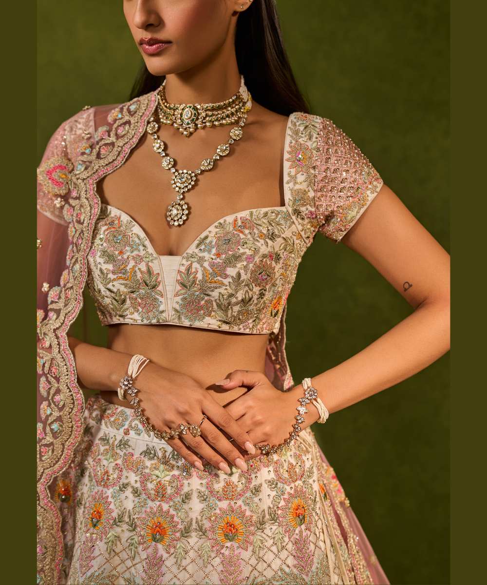 KIARA LEHENGA - Ivory organza lehenga adorned with intricate zari thread, sequence, and pearl embroidery paired with a stunning floral embellished blouse -  Leher by Chamee and Palak