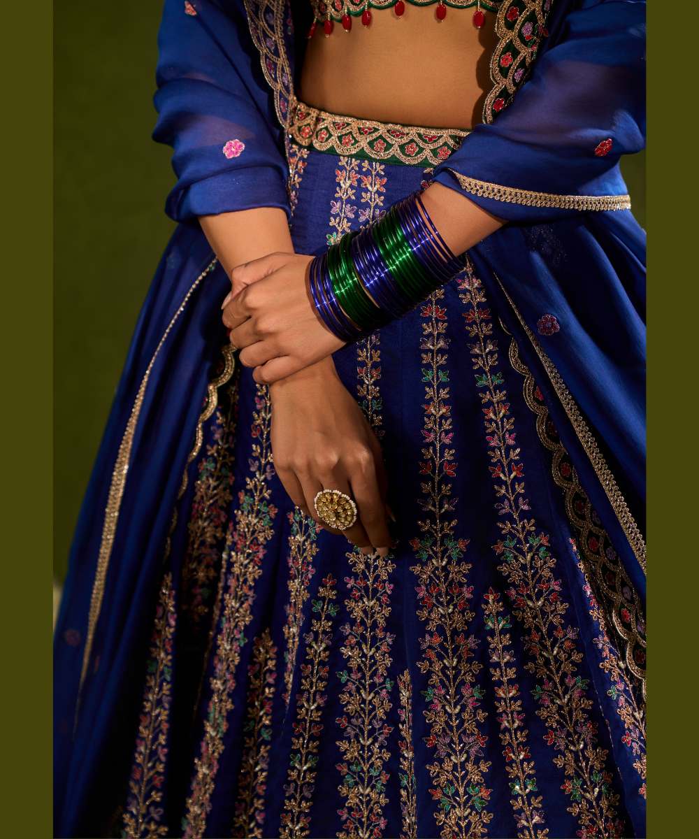 OORJA LEHENGA - Blue and green soft silk lehenga exquisitely embellished with vibrant resham, zari, pearls, and sequence work, in a graceful scallop pattern paired with a green, intricately embroidered plunging-neck blouse - Leher by Chamee and Palak