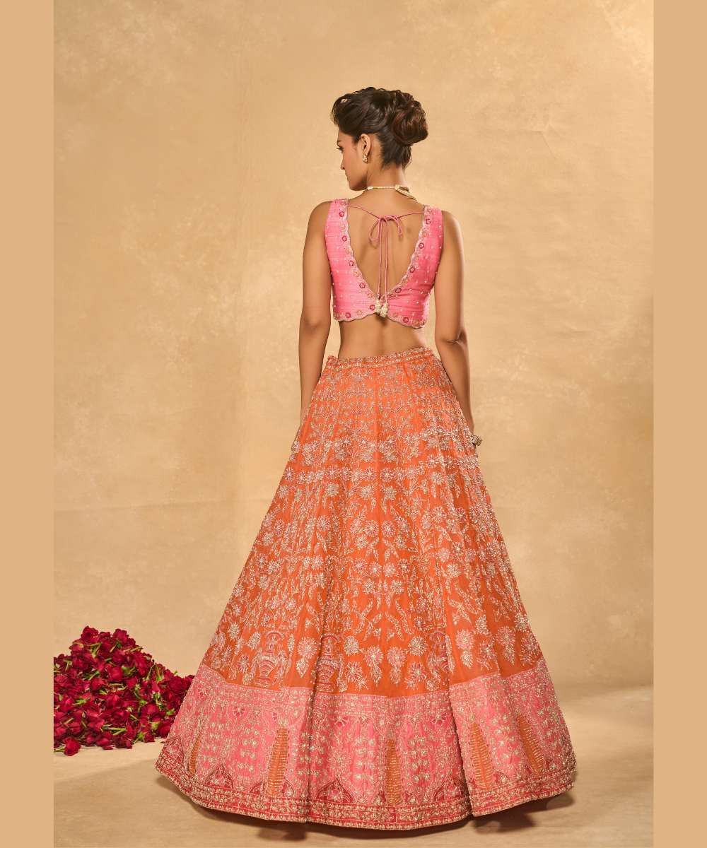 MAHIRA LEHENGA - Orange organza lehenga exquisitely embellished with a pink appliqué hem encrusted in intricate zari, resham, pearl, and glass bead paired with a delicately scalloped V-neck blouse - Leher by Chamee and Palak