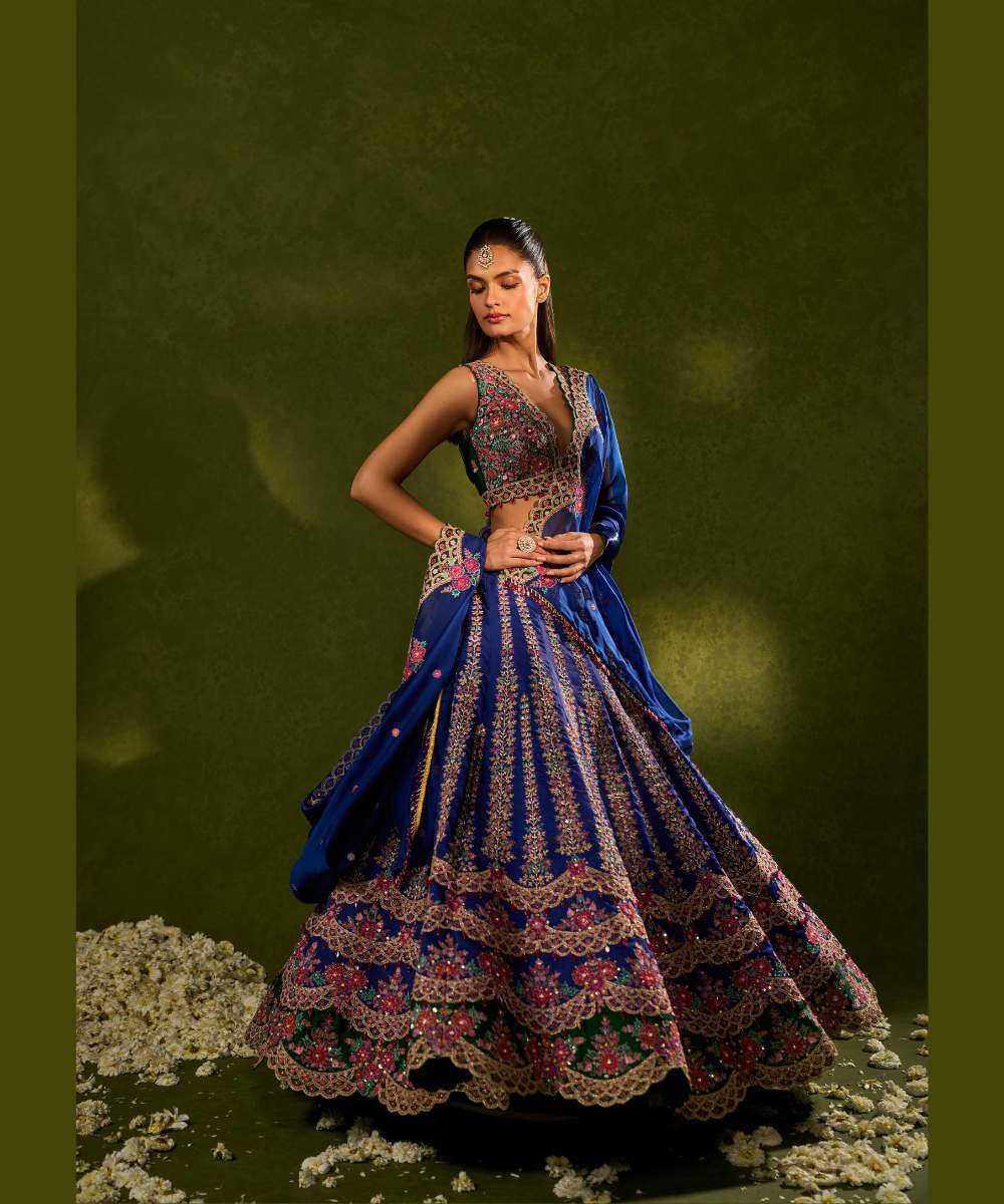 OORJA LEHENGA - Blue and green soft silk lehenga exquisitely embellished with vibrant resham, zari, pearls, and sequence work, in a graceful scallop pattern paired with a green, intricately embroidered plunging-neck blouse - Leher by Chamee and Palak