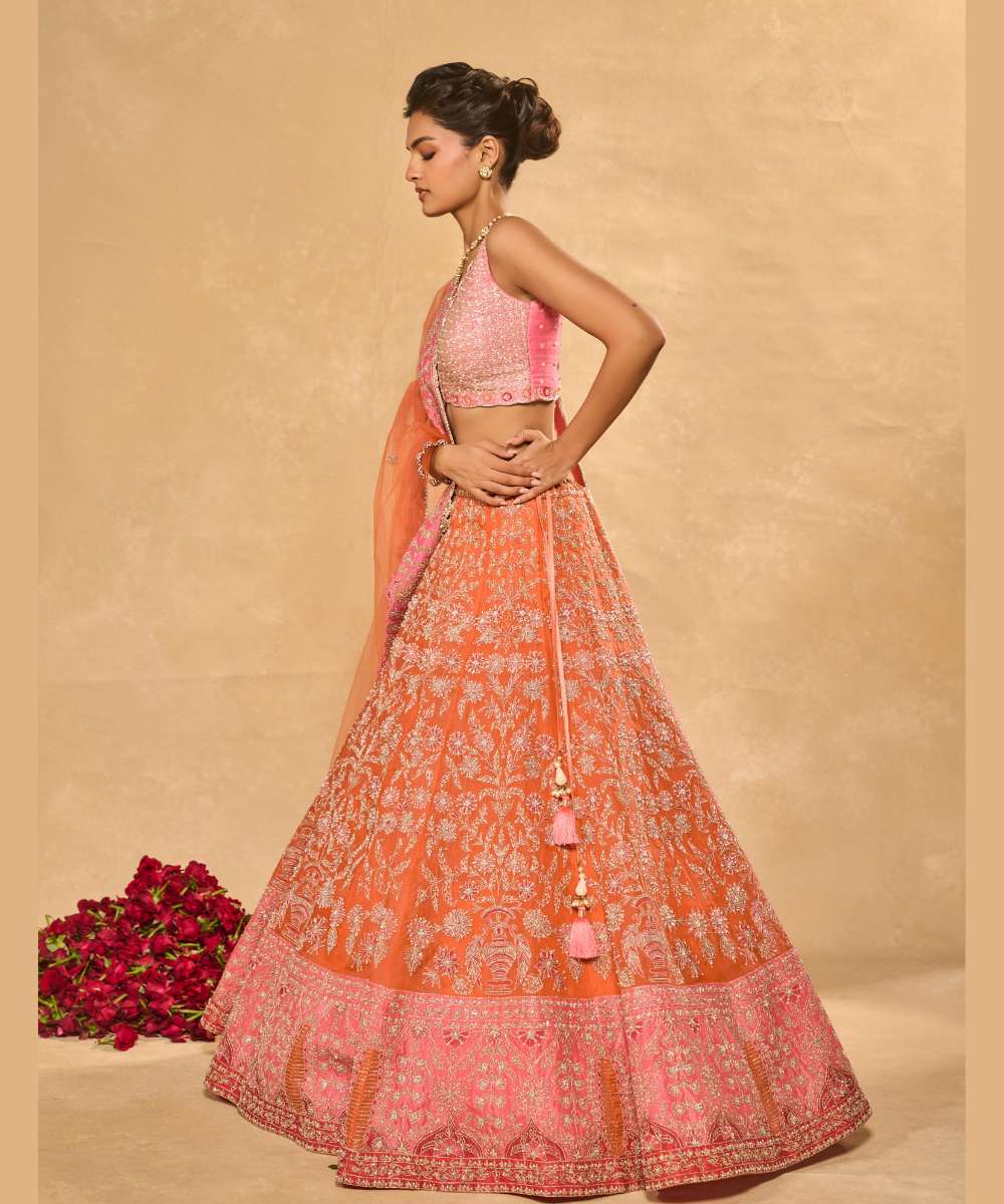MAHIRA LEHENGA - Orange organza lehenga exquisitely embellished with a pink appliqué hem encrusted in intricate zari, resham, pearl, and glass bead paired with a delicately scalloped V-neck blouse - Leher by Chamee and Palak