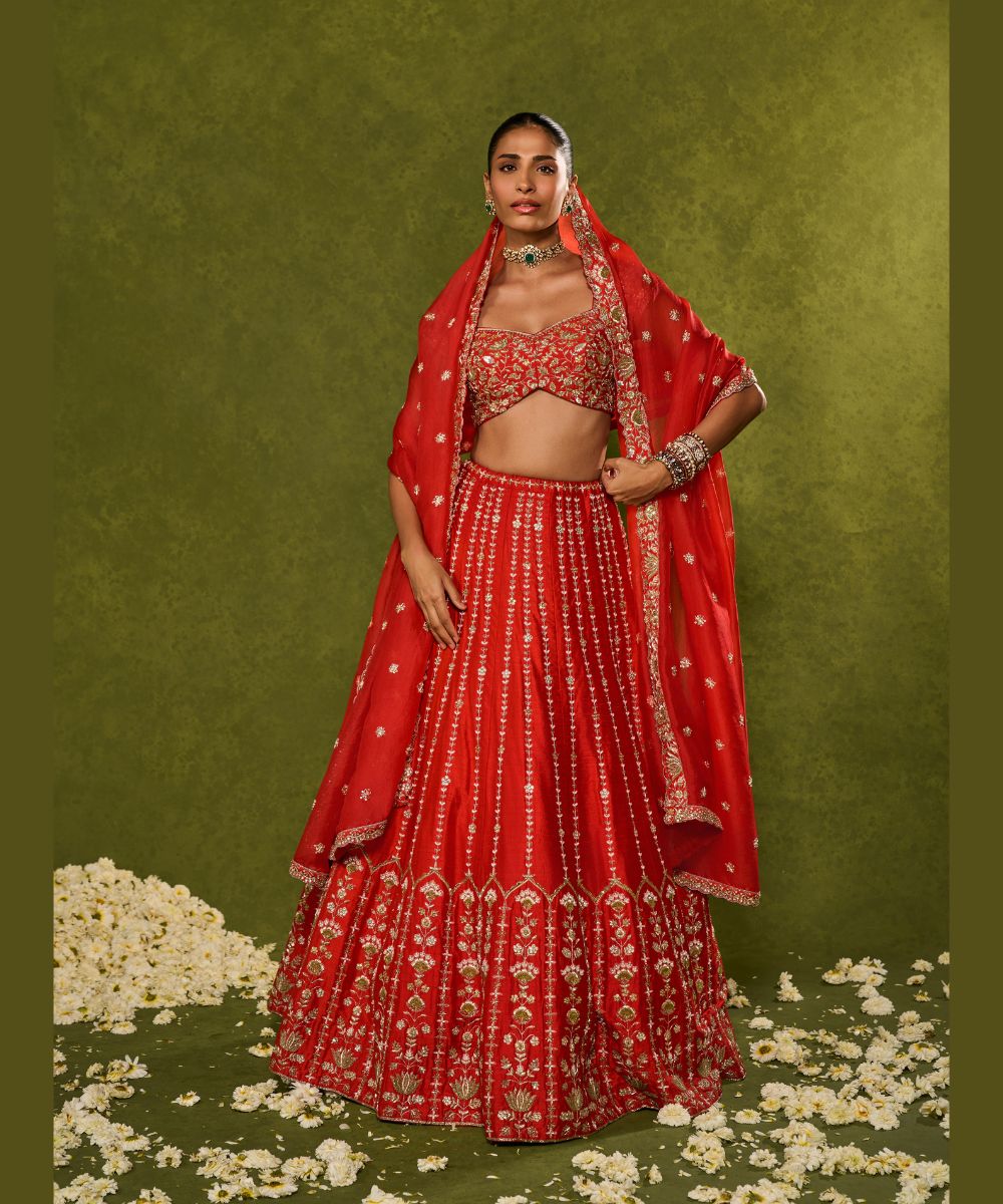 ANANDI LEHENGA - Red raw silk lehenga meticulously crafted with intricate resham, zardozi, pearl and glass beadwork paired with a zardozi-embellished floral work cap sleeve blouse -  Leher by Chamee and Palak