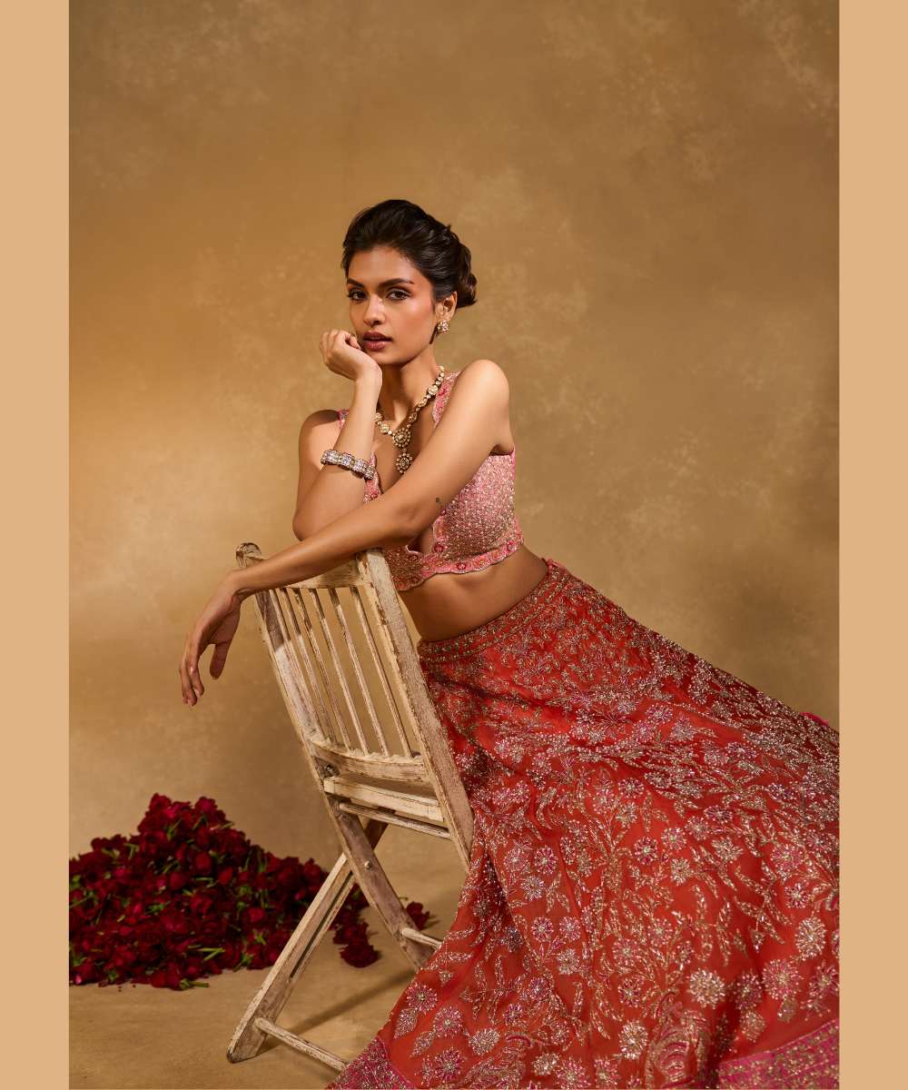 MAHIRA LEHENGA - Orange organza lehenga exquisitely embellished with a pink appliqué hem encrusted in intricate zari, resham, pearl, and glass bead paired with a delicately scalloped V-neck blouse - Leher by Chamee and Palak