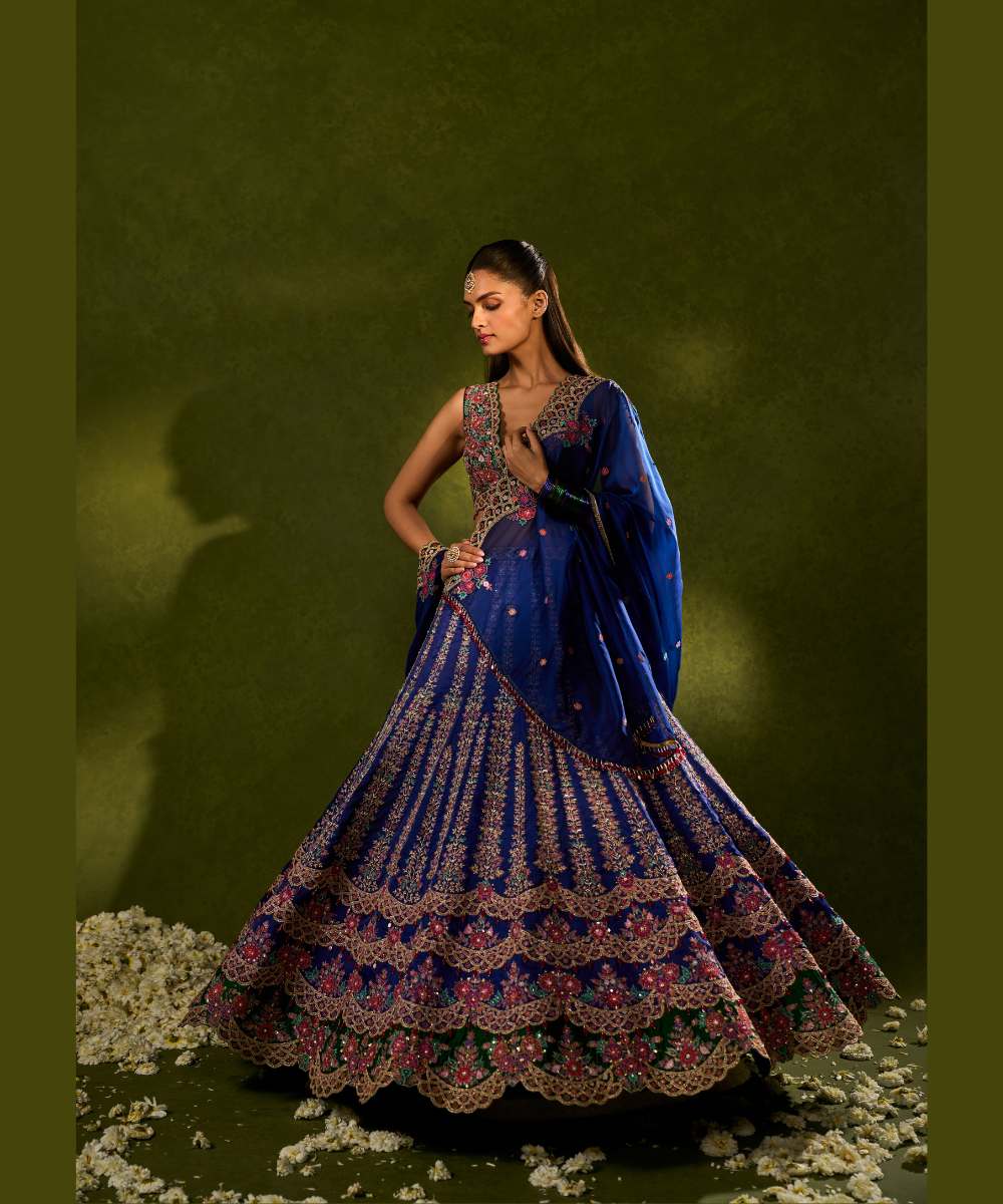 OORJA LEHENGA - Blue and green soft silk lehenga exquisitely embellished with vibrant resham, zari, pearls, and sequence work, in a graceful scallop pattern paired with a green, intricately embroidered plunging-neck blouse - Leher by Chamee and Palak