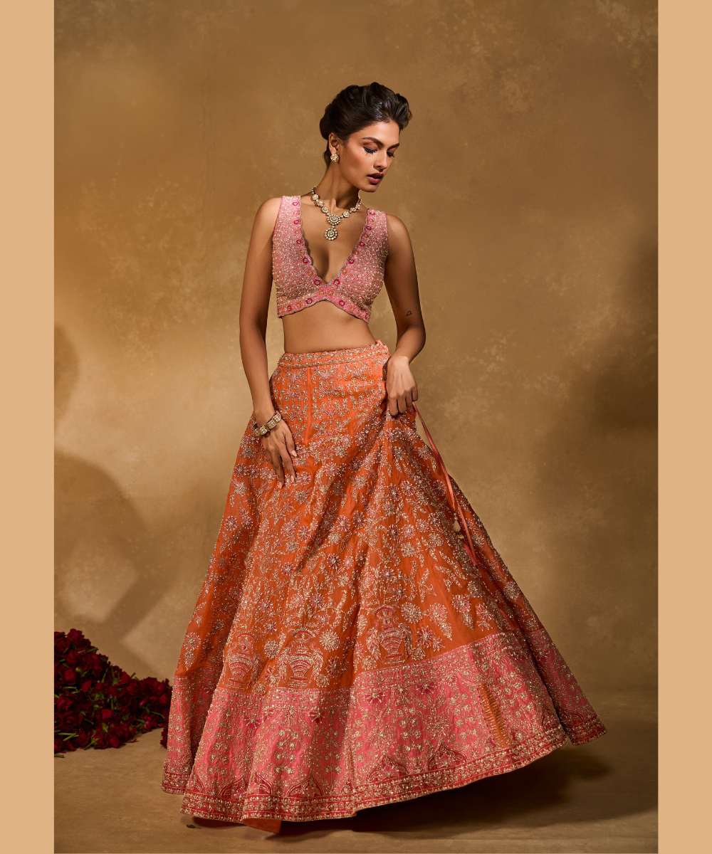 MAHIRA LEHENGA - Orange organza lehenga exquisitely embellished with a pink appliqué hem encrusted in intricate zari, resham, pearl, and glass bead paired with a delicately scalloped V-neck blouse - Leher by Chamee and Palak