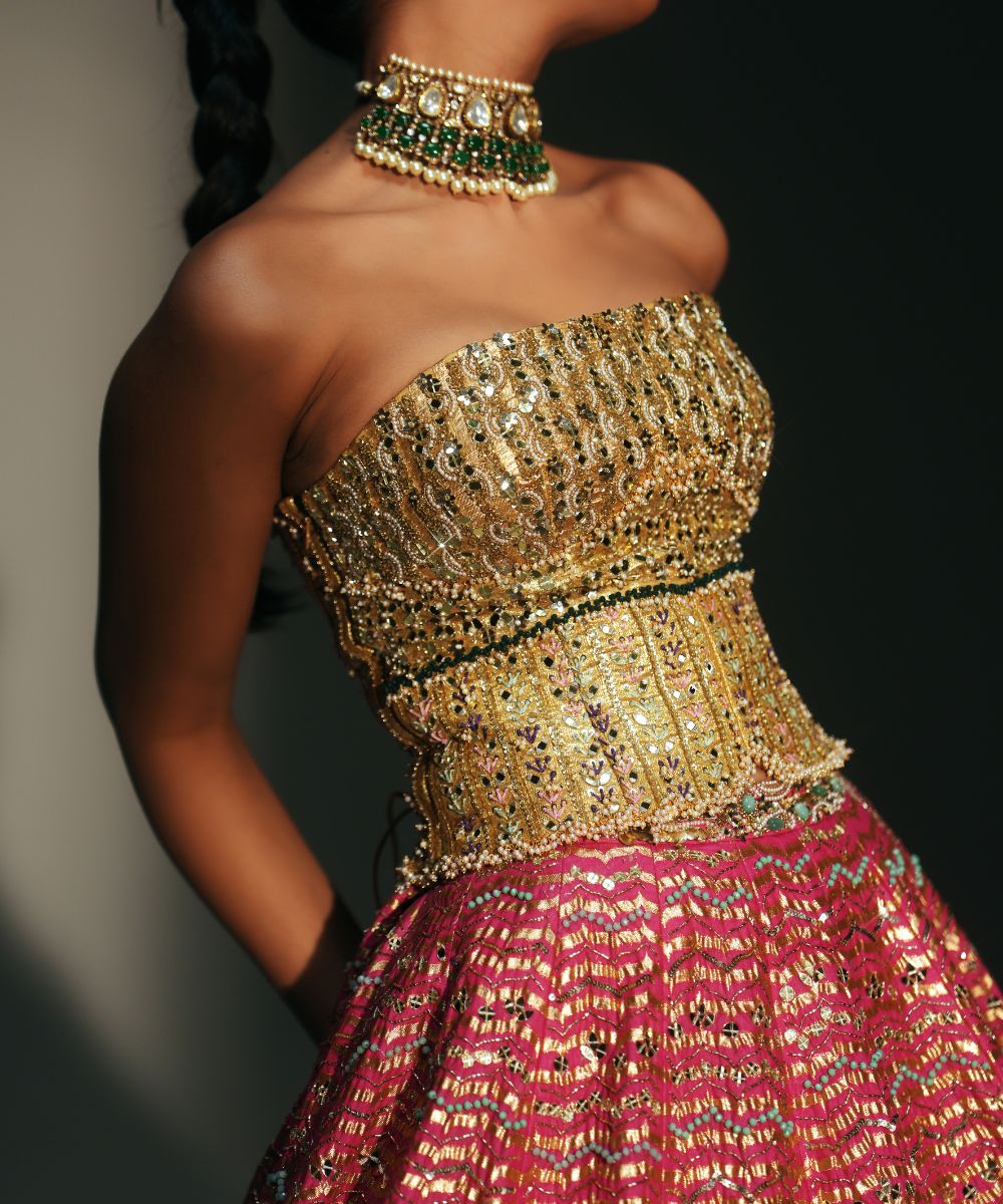 GARIMA - HAND EMBROIDERED RANI PINK LEHENGA WITH GOLDEN CORSET -  Mehfil by Mahima Mahajan