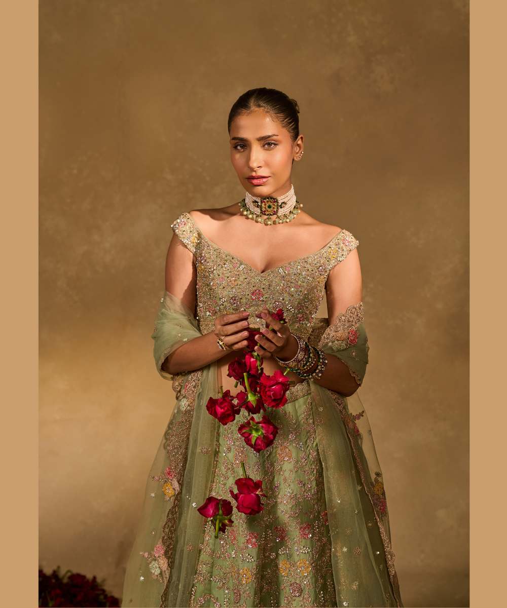 REVATI LEHENGA - Light Sage Green organza lehenga adorned with intricate zari thread, sequence, and pearl embroidery paired with a stunning floral-embellished off-shoulder blouse - Leher by Chamee and Palak