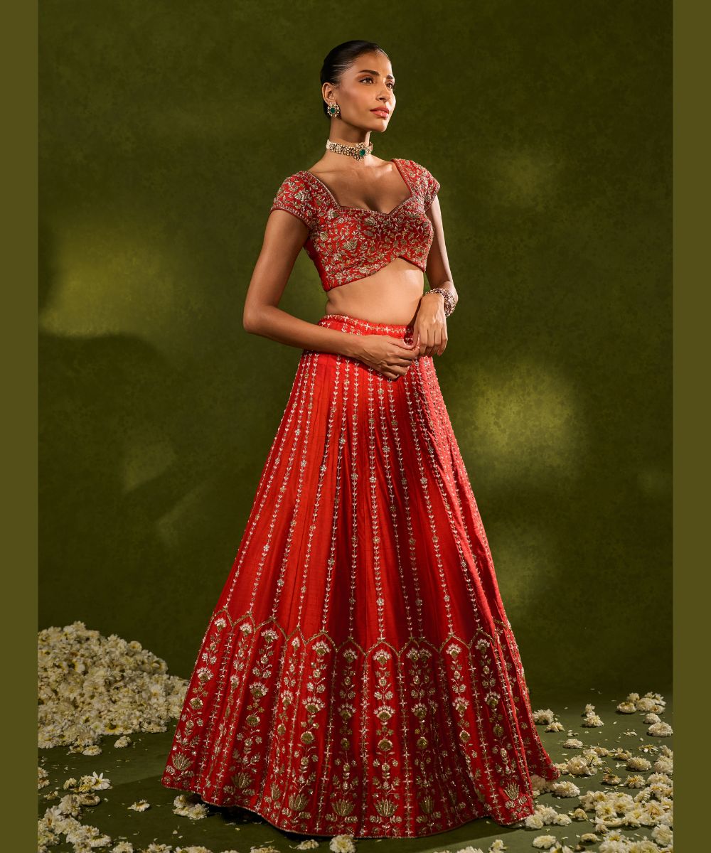 ANANDI LEHENGA - Red raw silk lehenga meticulously crafted with intricate resham, zardozi, pearl and glass beadwork paired with a zardozi-embellished floral work cap sleeve blouse -  Leher by Chamee and Palak