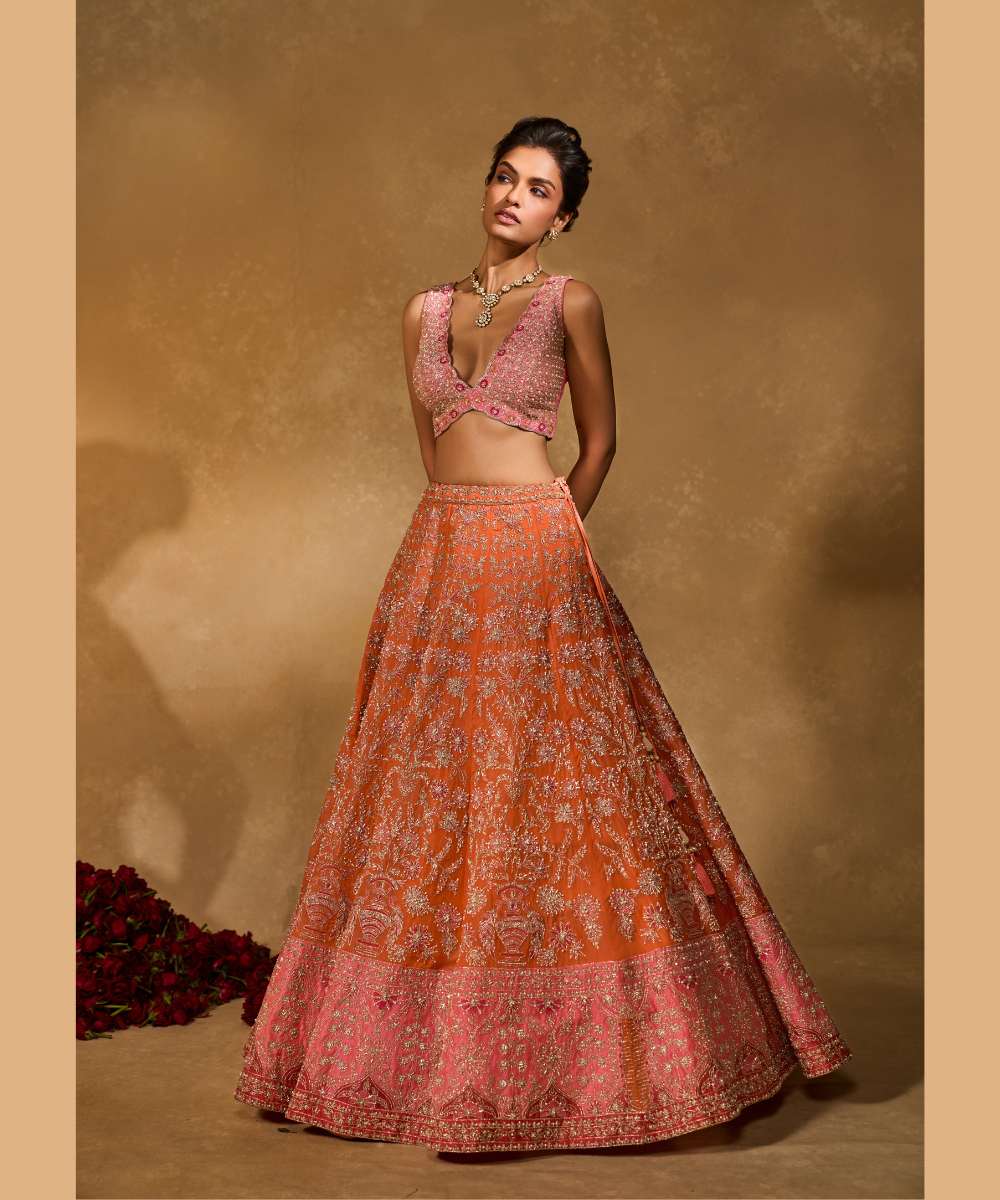 MAHIRA LEHENGA - Orange organza lehenga exquisitely embellished with a pink appliqué hem encrusted in intricate zari, resham, pearl, and glass bead paired with a delicately scalloped V-neck blouse - Leher by Chamee and Palak