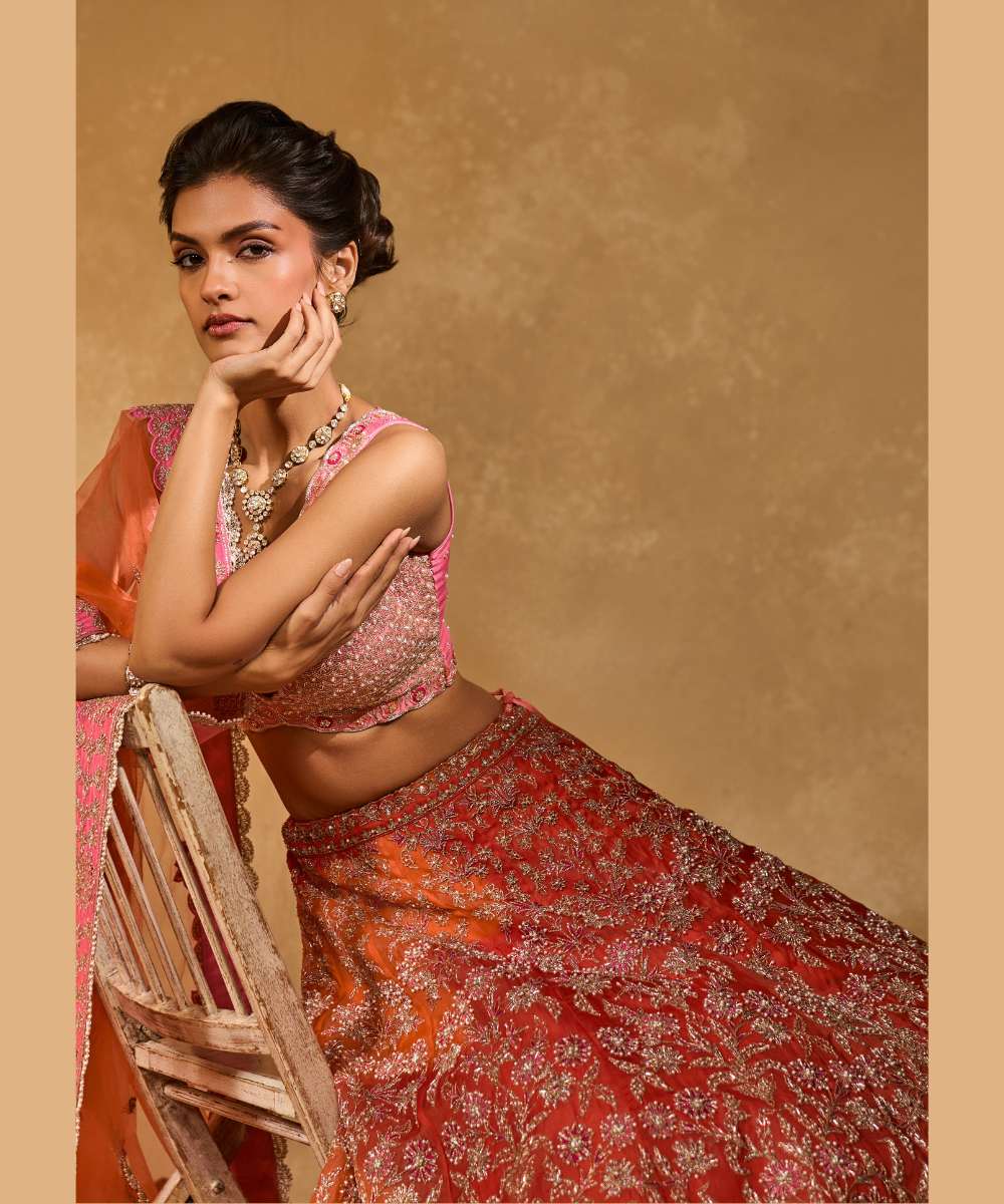 MAHIRA LEHENGA - Orange organza lehenga exquisitely embellished with a pink appliqué hem encrusted in intricate zari, resham, pearl, and glass bead paired with a delicately scalloped V-neck blouse - Leher by Chamee and Palak